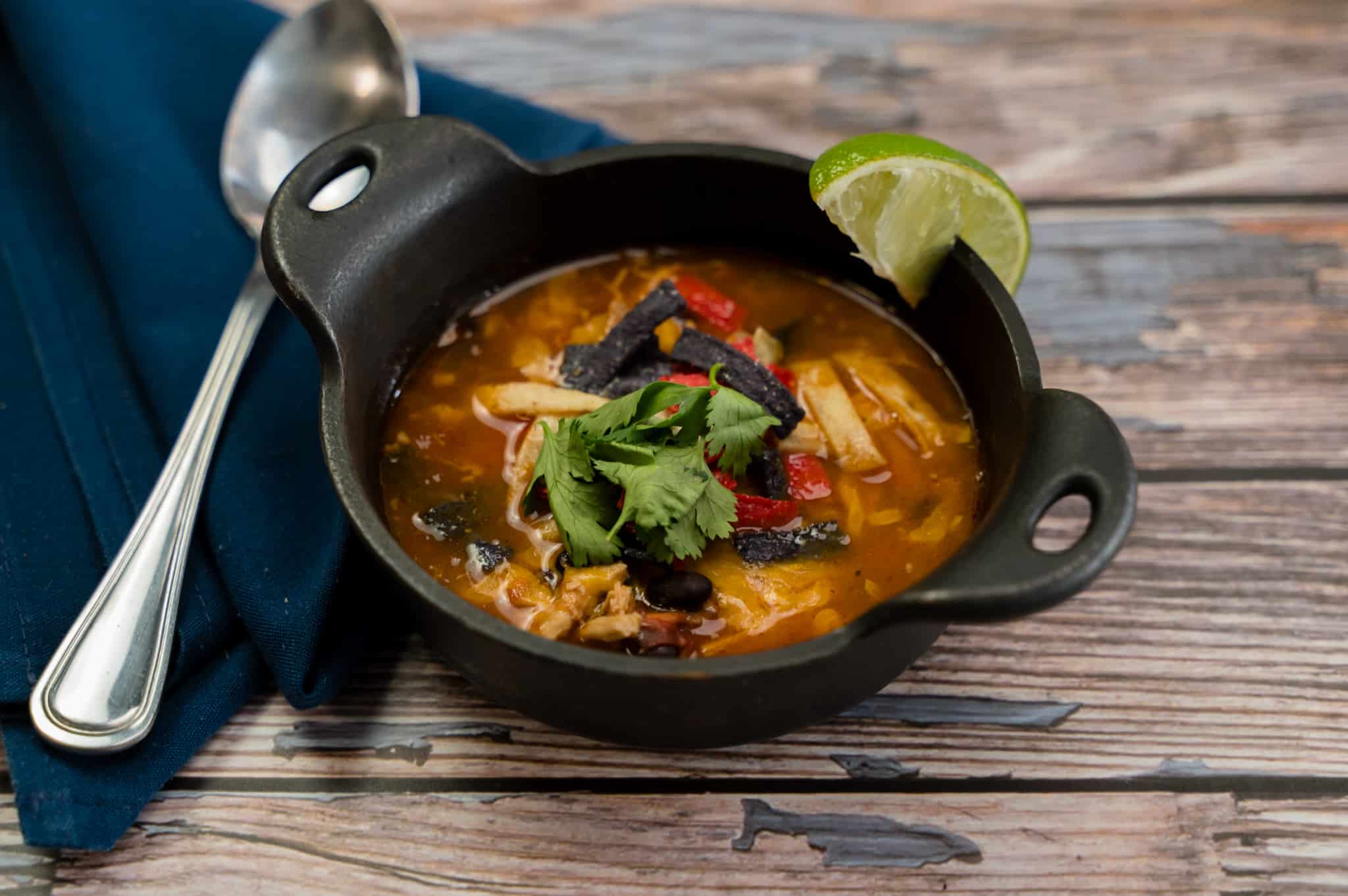 top down image of chicken tortilla soup in a cast iron bowl